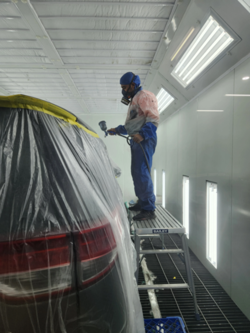 Spray painter applying base coat from an elevated platform