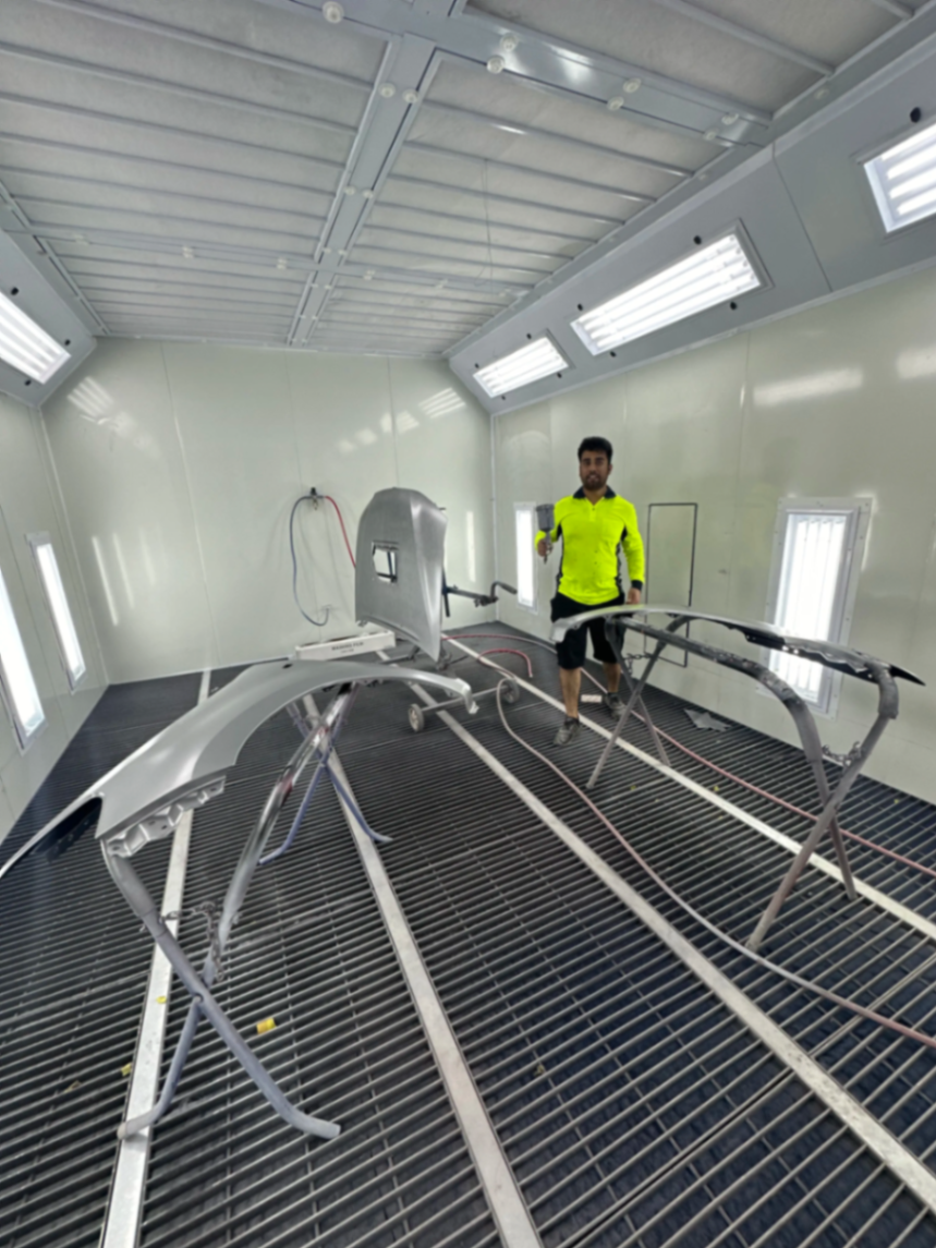 Freshly primed car panels drying on stands in the booth