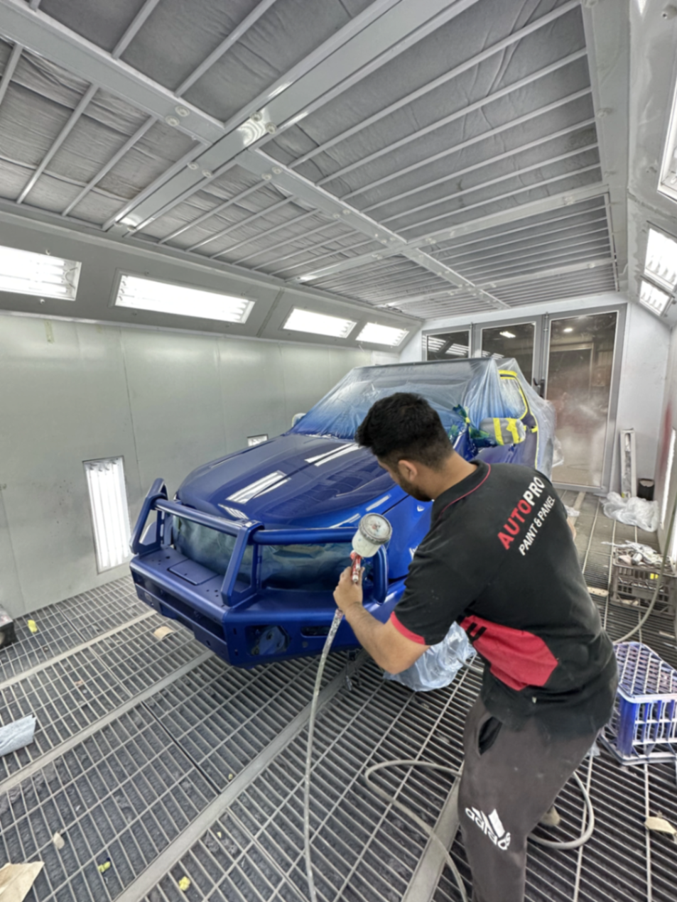 Spray painter applying a showroom finish to a luxury sedan in the Autopro Woodridge booth